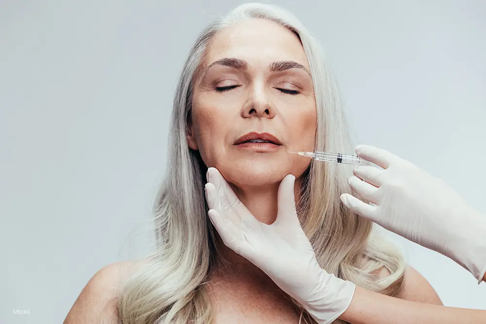 Mature woman with gray hair getting a face injection