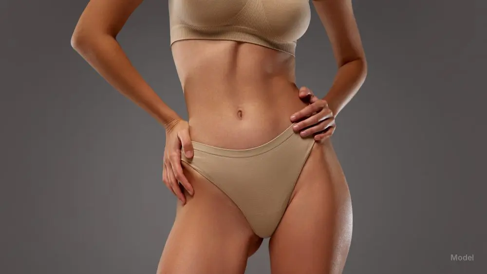 Close-up of woman's torso in beige lingerie against warm grey background