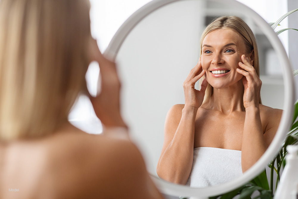 Mature woman touching her face in a mirror